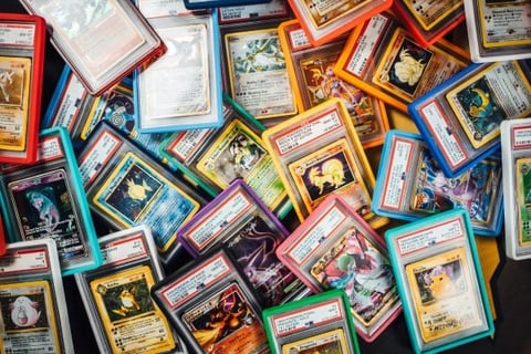 Colorful collection of trading cards with character artwork in multicolored protective sleeves arranged on white background